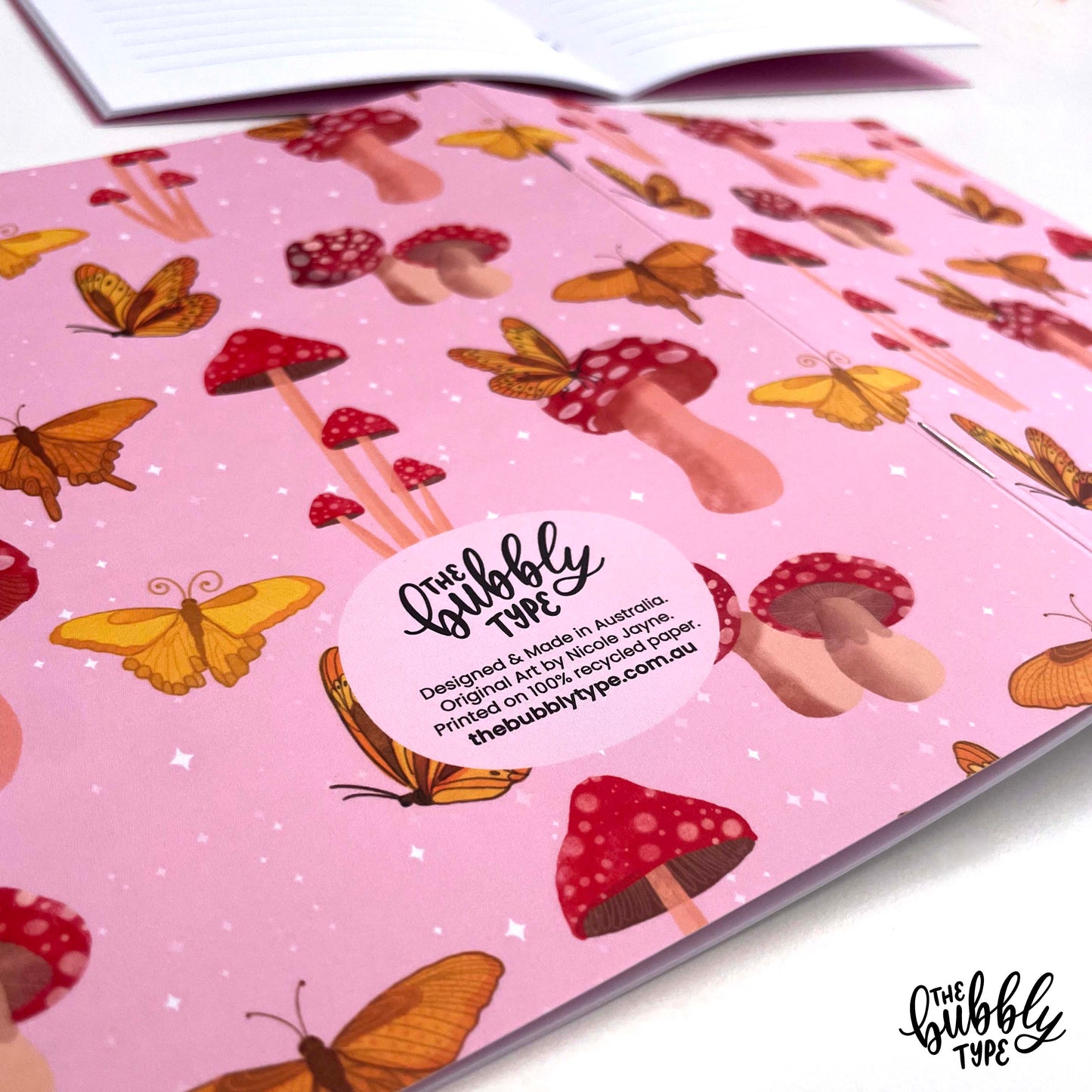 Handmade A5 notebook with mushroom and butterflies pattern cover, featuring original artwork by Nicole Jayne for The Bubbly Type, 32 lined pages on 120gsm premium uncoated paper, eco-friendly recycled matte finish, ideal for notes, journaling, and gifts.